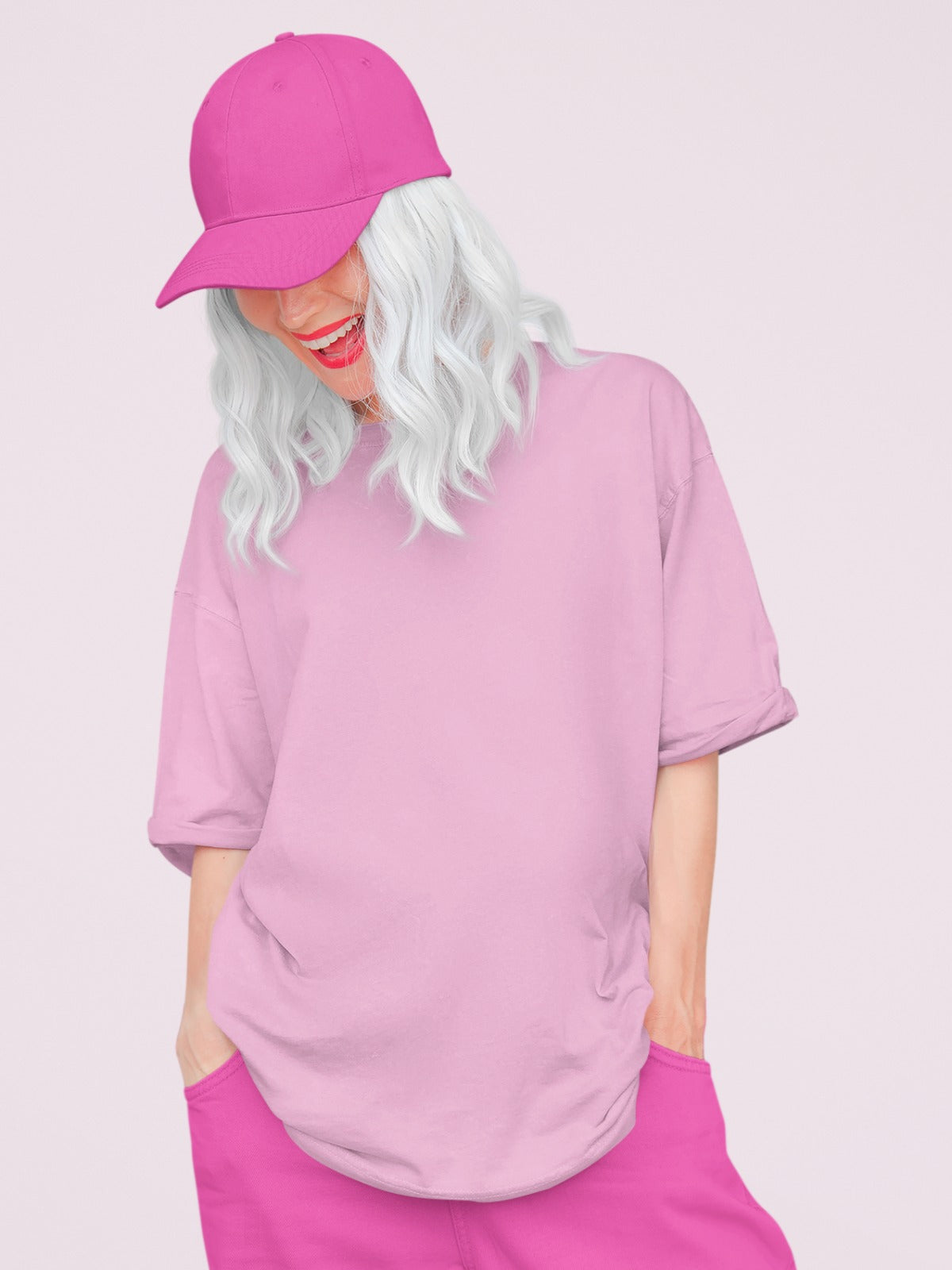 In this captivating image, a girl with striking white hair exudes confidence and style. She's adorned in our Premium Heavyweight Baby Pink Oversized Tee, which drapes effortlessly, oozing comfort and fashion-forward charm. To complete her look, she sports a chic dark pink cap and matching pants. Her attire effortlessly blends comfort with a trendy aesthetic, making a bold fashion statement.