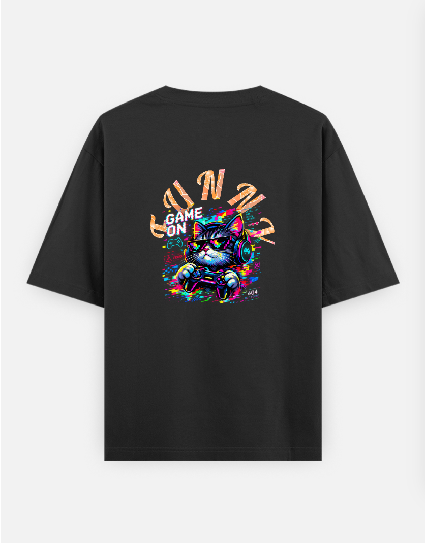 A pixelated cat wearing headphones and sunglasses plays a video game with a controller. The image features the text "GAM Oversized T-shirt (Back print) by @ktart31