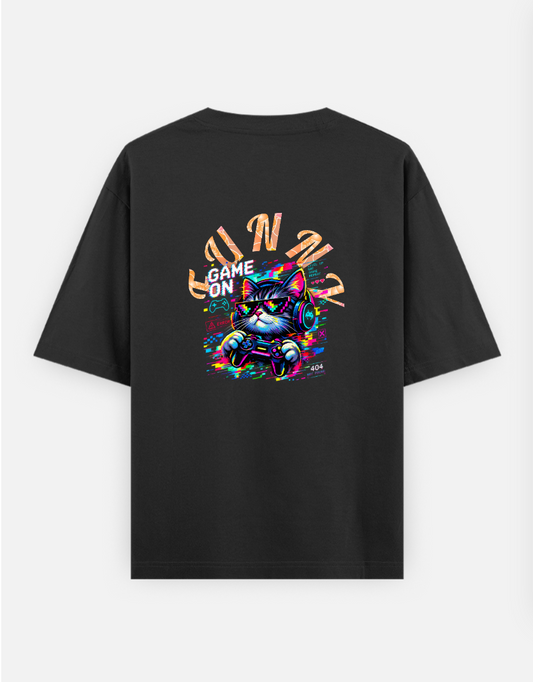 A pixelated cat wearing headphones and sunglasses plays a video game with a controller. The image features the text "GAM Oversized T-shirt (Back print) by @ktart31