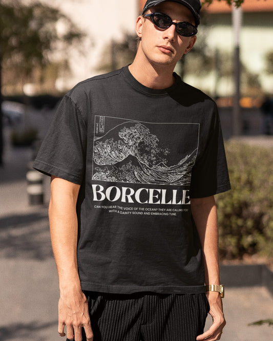 Elevate your style with our black oversized unisex t-shirt featuring a captivating Japanese-style wave in white. Titled "BORCELLE," the design is accompanied by the message, "Can you hear the voice of the ocean? They are calling you with a dainty sound and embracing tune," adding enchantment. Crafted with premium materials, this comfortable and artistic t-shirt celebrates the ocean's soothing power, making a bold fashion statement.