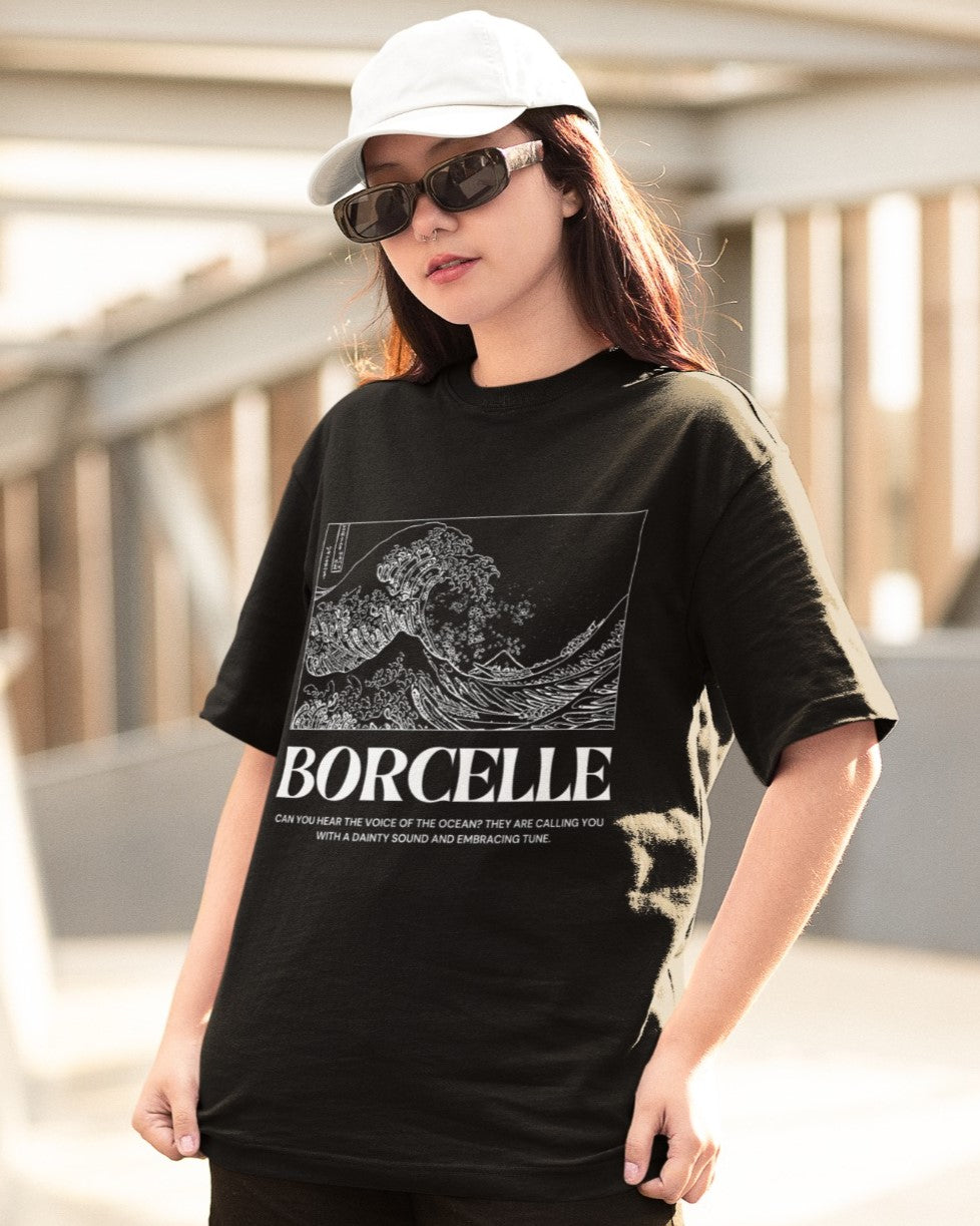 Elevate your style with our black oversized unisex t-shirt featuring a Japanese-style white wave and the title "BORCELLE." The message "Can you hear the voice of the ocean? They are calling you with a dainty sound and embracing tune" adds enchantment. Crafted for comfort and unique style, this artistic t-shirt celebrates nature's allure. Embrace the ocean's voice and make a bold statement with BORCELLE!