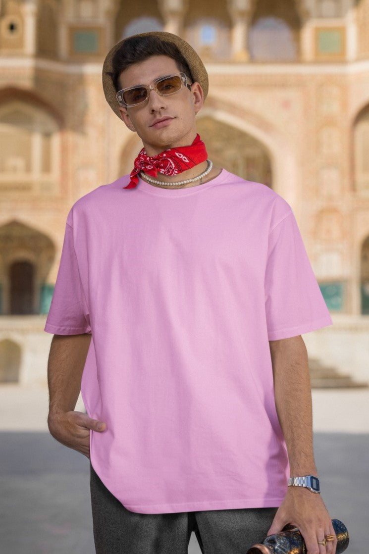 In this striking image, a confident and stylish guy dons our Premium Heavyweight Baby Pink Oversized Tee, exuding effortless cool. He elevates the look with a vibrant red bandana stylishly tied around his neck, adding a dash of attitude. Fashionable shades protect his eyes, and a trendy hat completes the ensemble. His outfit harmoniously blends comfort and flair, making a bold and memorable fashion statement.