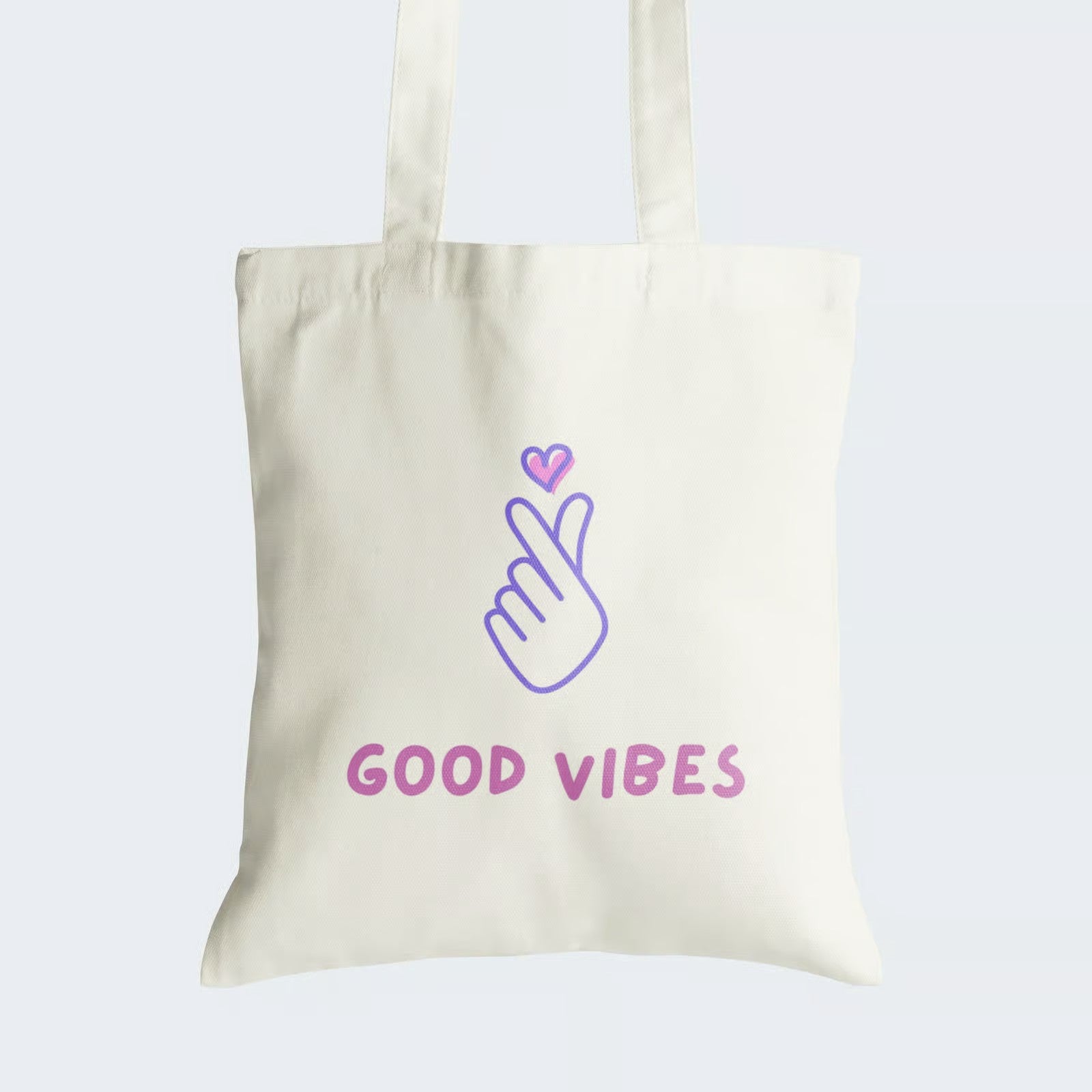Elevate your style and radiate positivity with our "Good Vibes" Cotton Canvas Tote Bag. This tote features an endearing graphic of the mini heart hand gesture beneath a heart symbol, complemented by the inspiring caption "Good Vibes." With durable craftsmanship and a secure zipper closure, it's not just a bag; it's a statement of spreading positivity. Order yours today and carry good vibes everywhere!