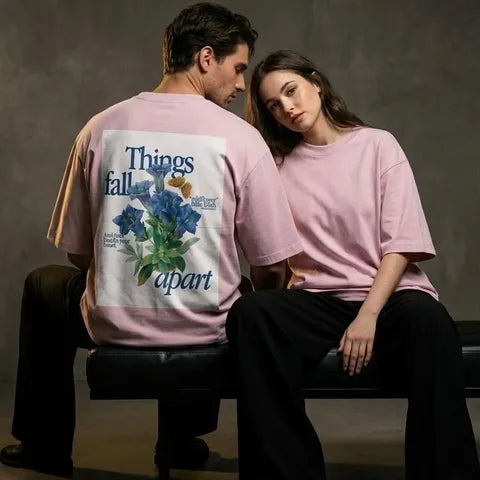 Two people wearing matching pink t-shirts with a floral design and text.
