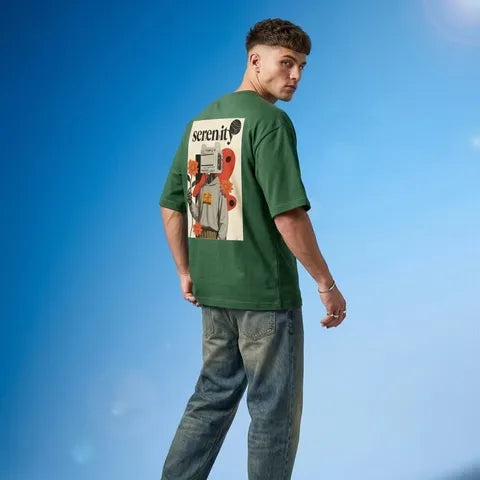Man wearing a green t-shirt with a graphic design against a blue sky