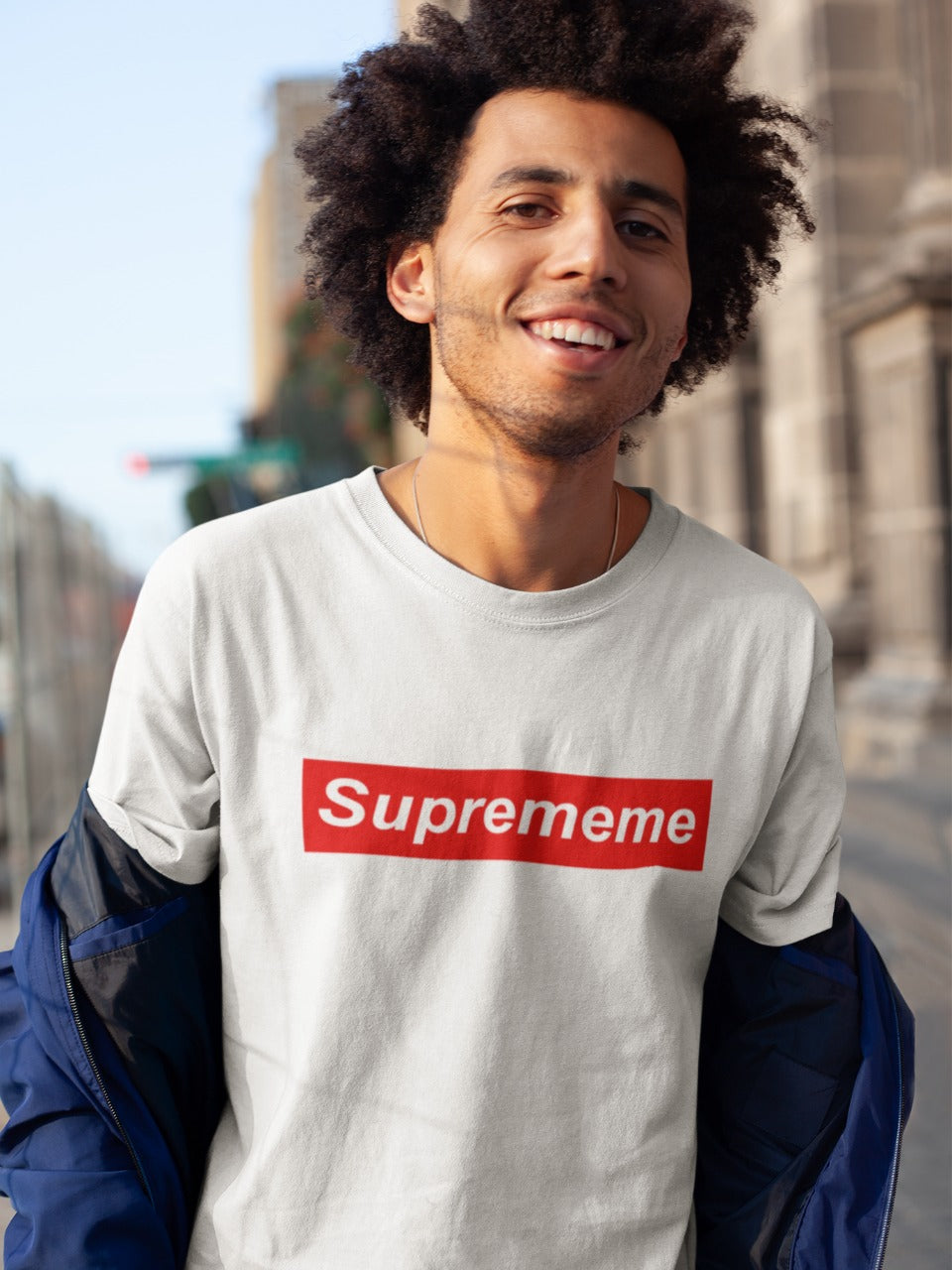 smiling man with curly hair wearing a white tshirt with suprememe printed on it in red colour
