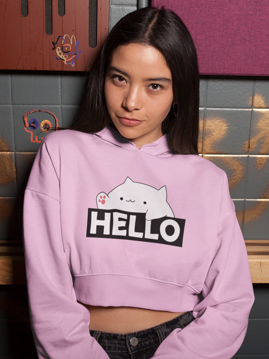 Girl wearing a baby pink crop hoodie with bongo cat saying hello printed on it, cute funny meme