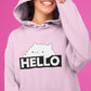 Girl wearing baby pink hoodie with bongo cat saying hello printed on it, the girl's face is half covered with the hood and she is smiling, cute funny memes