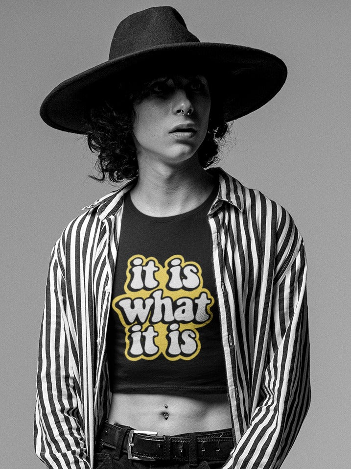 black & white photo of girl with black hat wearing a vertical stripes shirt with a crop top inside with it is what it is printed on it, fun sayings, relatable sarcastic memes