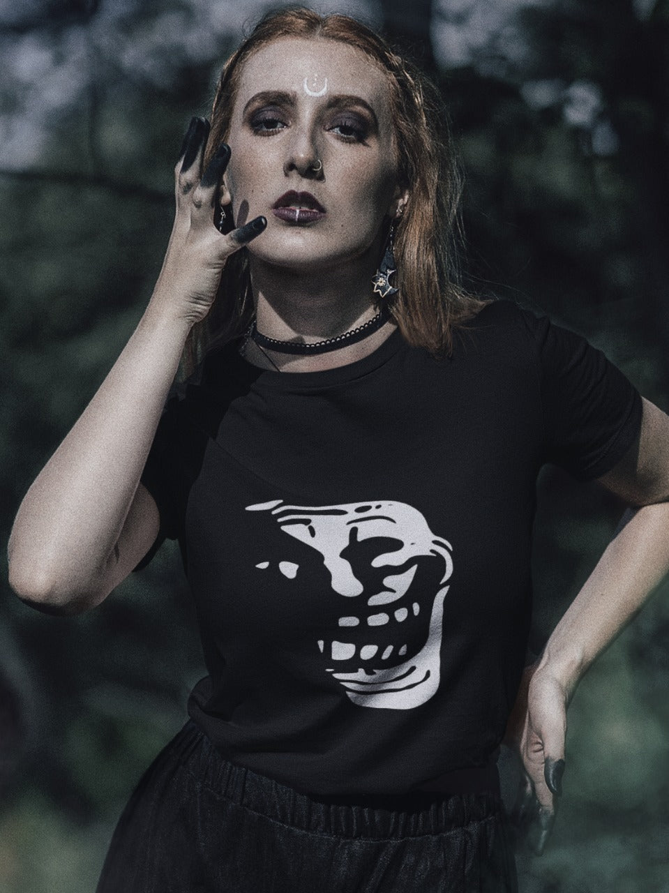 girl with black paint on her fingers and a lip ring and nose ring wearing a black tshirt with smiling troll face in dark silhouette printed on it in white colour, dark, sarcastic, gothic memes