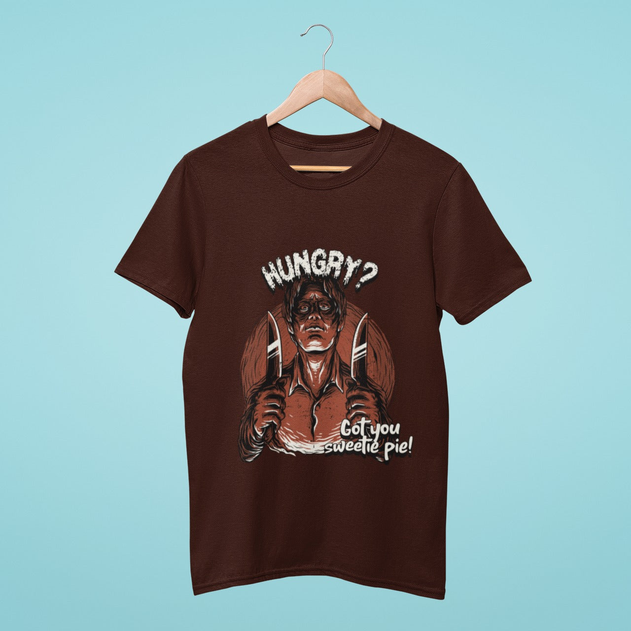 Looking for a humorous and edgy t-shirt? Check out this brown tee featuring a graphic of a comically wicked man holding up two knives and taunting "Hungry? Got you sweetie pie!" Perfect for those with a dark sense of humor, this shirt is sure to turn heads and spark conversations. Get your wickedly cool look today!